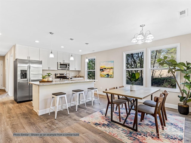 dining space with light wood-type flooring, visible vents, recessed lighting, baseboards, and a chandelier
