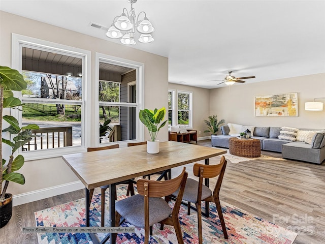 dining area with visible vents, baseboards, wood finished floors, and ceiling fan with notable chandelier