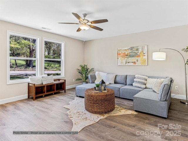 living area with wood finished floors, a ceiling fan, visible vents, and baseboards