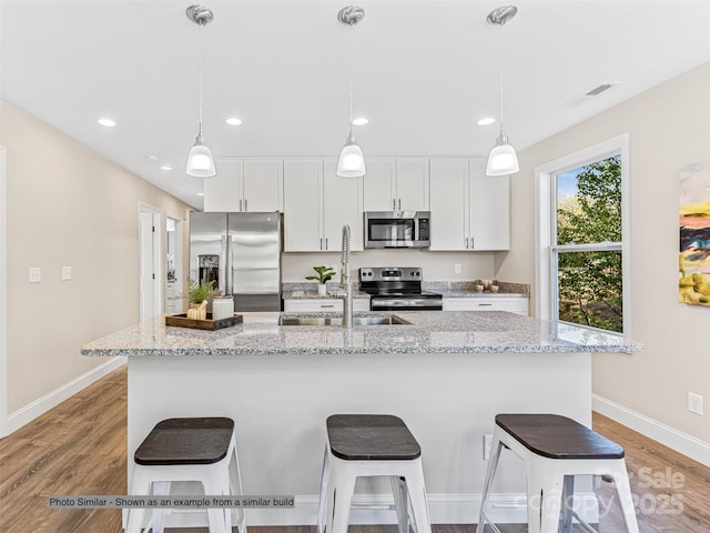 kitchen featuring a kitchen breakfast bar, light wood-style flooring, a kitchen island with sink, and stainless steel appliances