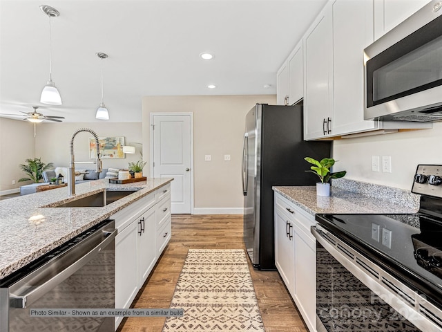 kitchen featuring pendant lighting, a sink, stainless steel appliances, white cabinets, and light wood finished floors
