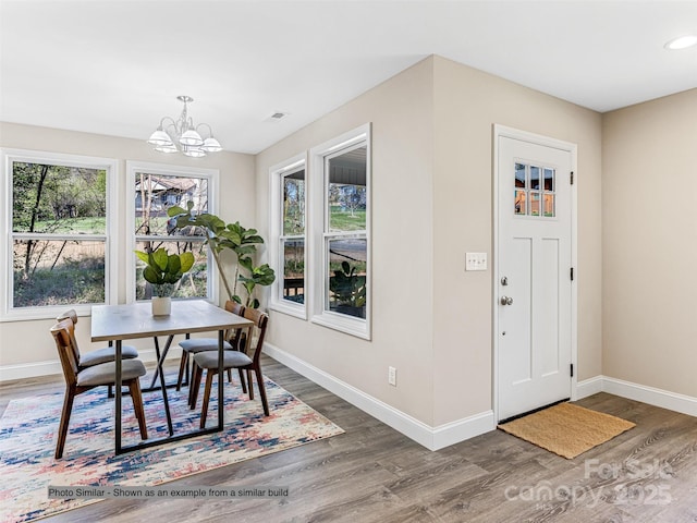 dining space with visible vents, baseboards, an inviting chandelier, and wood finished floors