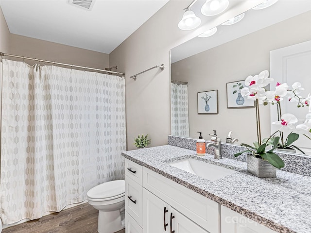 bathroom with vanity, a shower with curtain, wood finished floors, visible vents, and toilet