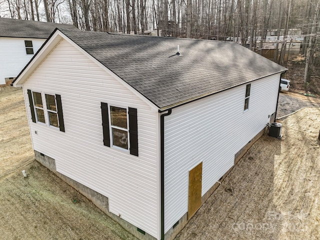 view of side of property featuring crawl space, roof with shingles, and central AC
