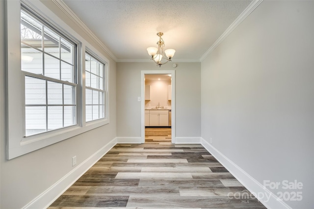 unfurnished dining area featuring hardwood / wood-style flooring, ornamental molding, a textured ceiling, and an inviting chandelier