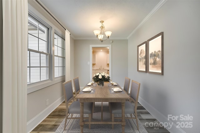 dining room featuring a notable chandelier, hardwood / wood-style flooring, ornamental molding, and sink