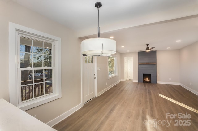 unfurnished living room featuring ceiling fan, a large fireplace, and wood-type flooring