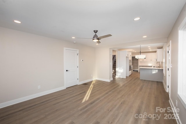 unfurnished living room with ceiling fan, dark hardwood / wood-style floors, and sink