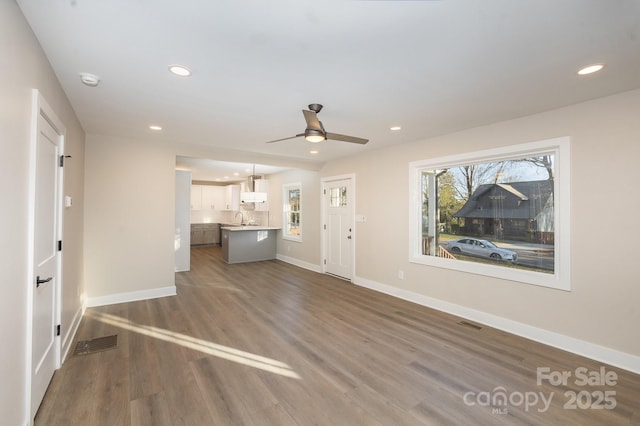 unfurnished living room featuring ceiling fan, dark hardwood / wood-style flooring, and sink