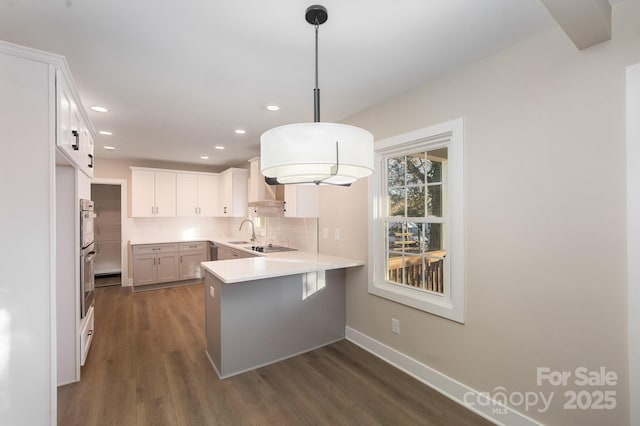 kitchen featuring a breakfast bar, pendant lighting, sink, white cabinets, and kitchen peninsula