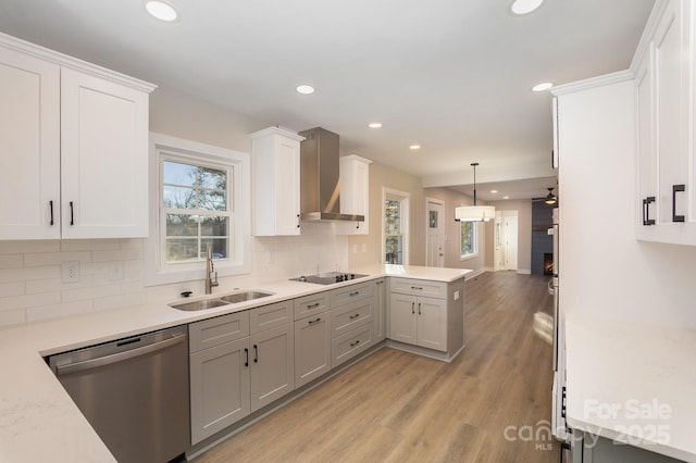 kitchen featuring sink, gray cabinetry, hanging light fixtures, stainless steel dishwasher, and wall chimney exhaust hood