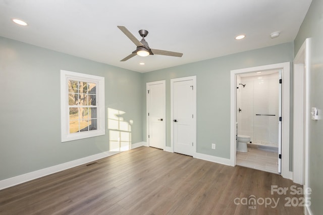 unfurnished bedroom with multiple closets, ceiling fan, connected bathroom, and hardwood / wood-style floors