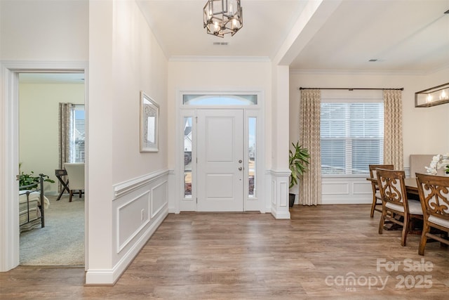 foyer featuring ornamental molding, a chandelier, and hardwood / wood-style floors