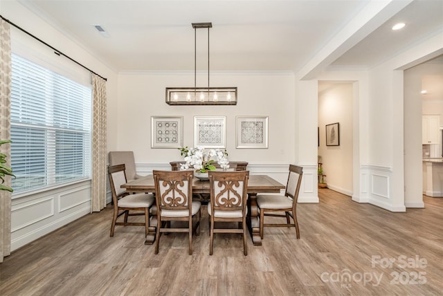 dining area with crown molding and hardwood / wood-style floors