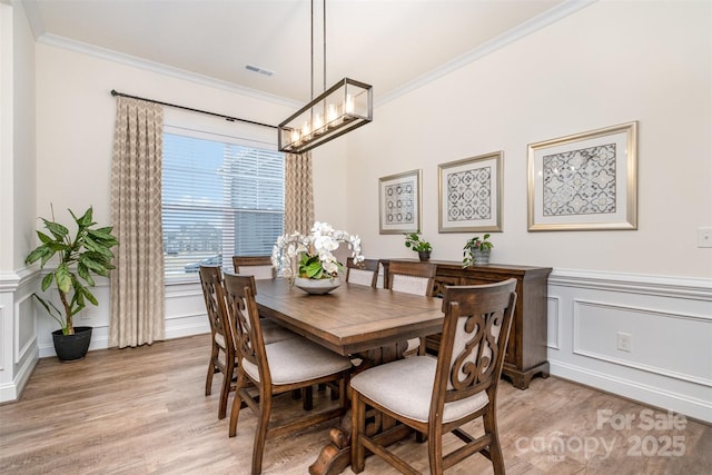 dining space with crown molding, a chandelier, and light wood-type flooring