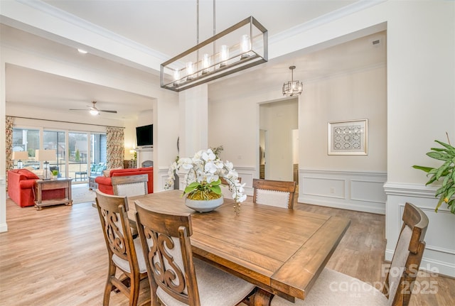 dining space featuring crown molding, ceiling fan with notable chandelier, and light wood-type flooring