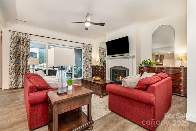 living room featuring crown molding, ceiling fan, and light hardwood / wood-style floors