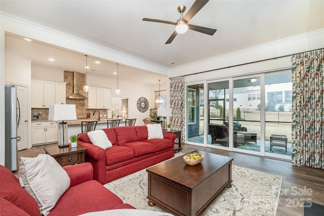 living room with ornamental molding, sink, ceiling fan, and light hardwood / wood-style flooring