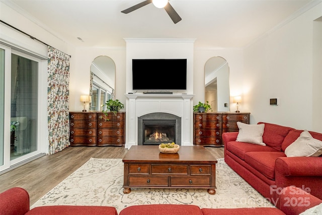 living room with crown molding, wood-type flooring, and ceiling fan