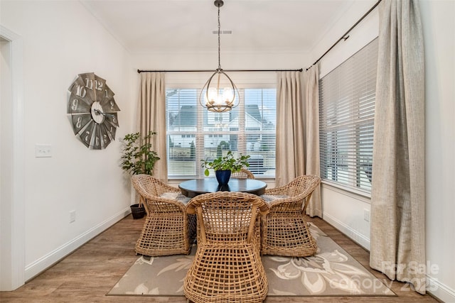 dining area featuring an inviting chandelier, wood-type flooring, and ornamental molding