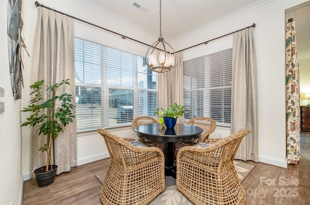 dining area featuring crown molding, an inviting chandelier, and hardwood / wood-style floors