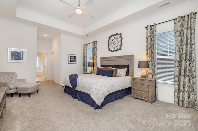 carpeted bedroom featuring a raised ceiling, ornamental molding, ensuite bathroom, and ceiling fan