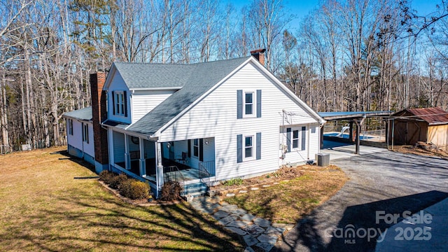 view of front of property featuring covered porch, aphalt driveway, a chimney, and a front yard