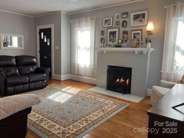 living room with crown molding, a brick fireplace, hardwood / wood-style floors, and a textured ceiling