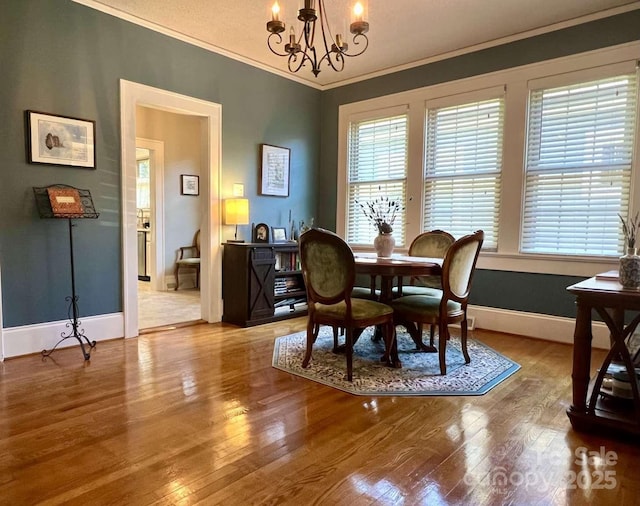 dining space with an inviting chandelier, wood-type flooring, crown molding, and a wealth of natural light