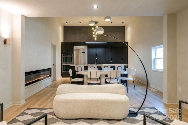 living room featuring sink, light wood-type flooring, and a high ceiling