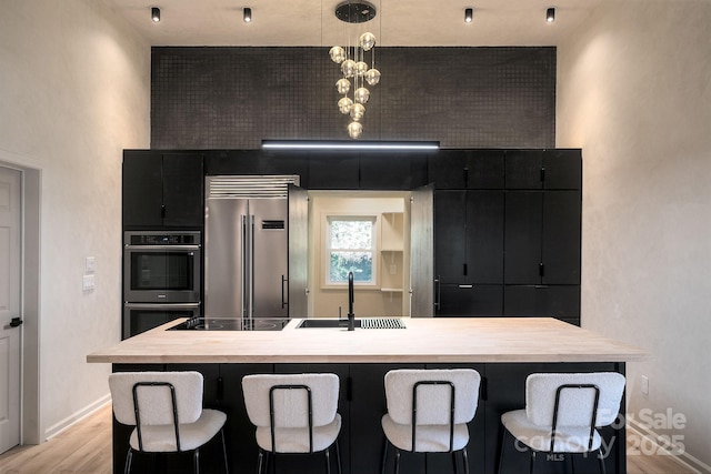 kitchen featuring sink, light hardwood / wood-style flooring, appliances with stainless steel finishes, hanging light fixtures, and a kitchen island