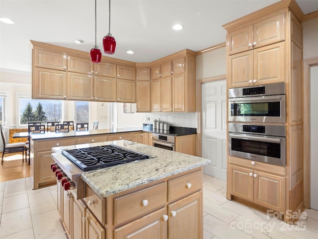 kitchen featuring hanging light fixtures, stainless steel appliances, tasteful backsplash, a kitchen island, and light brown cabinetry