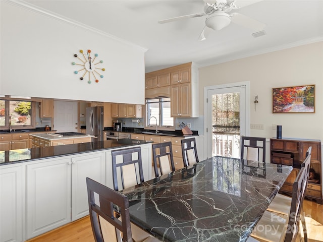 dining space with ornamental molding, sink, and light wood-type flooring