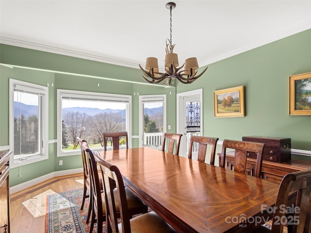 dining space with crown molding, a notable chandelier, and light hardwood / wood-style flooring