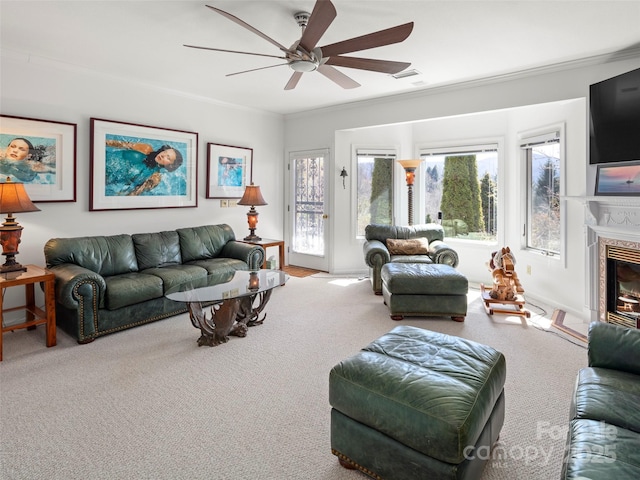 living room featuring ornamental molding, carpet floors, ceiling fan, and a fireplace