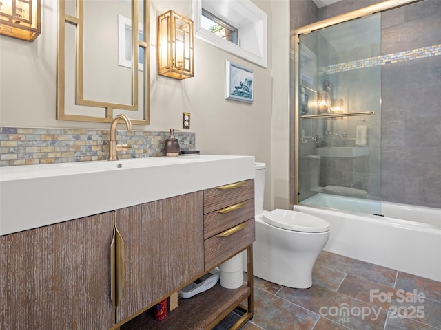 full bathroom with bath / shower combo with glass door, vanity, backsplash, and toilet