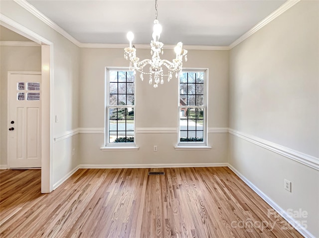 unfurnished dining area with ornamental molding, an inviting chandelier, and light hardwood / wood-style floors