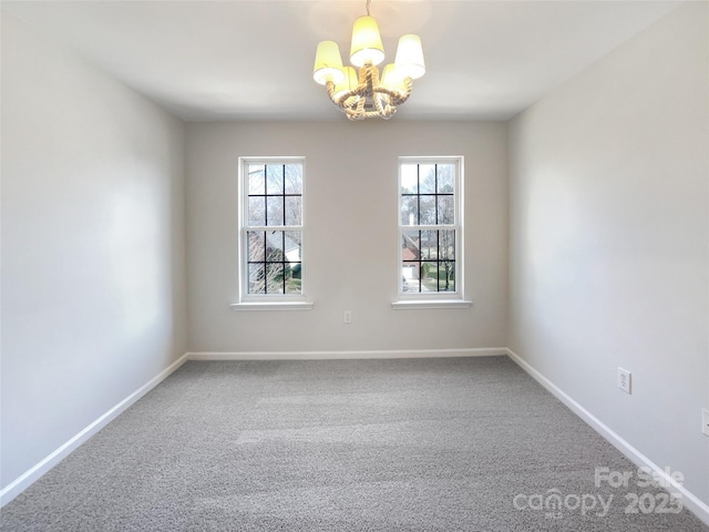 carpeted spare room featuring a chandelier