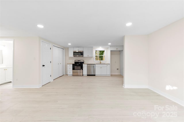 unfurnished living room featuring sink and light hardwood / wood-style flooring