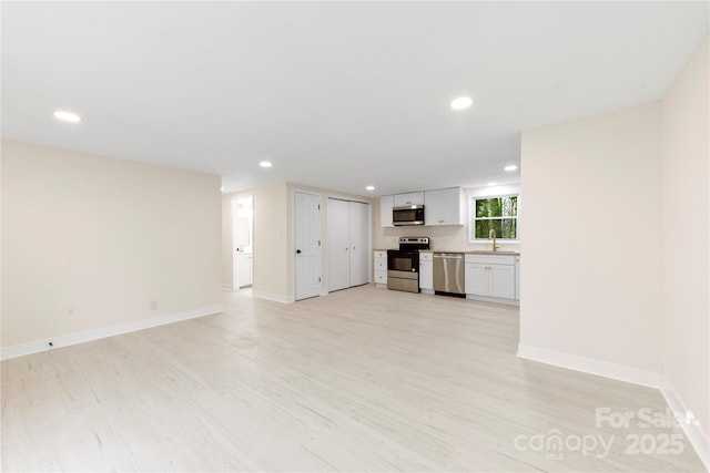 unfurnished living room with sink and light hardwood / wood-style floors