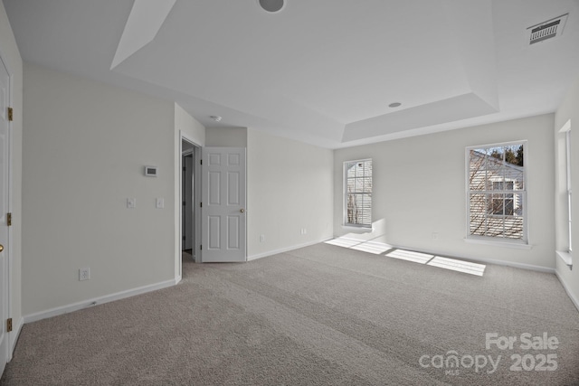 empty room featuring light carpet and a tray ceiling