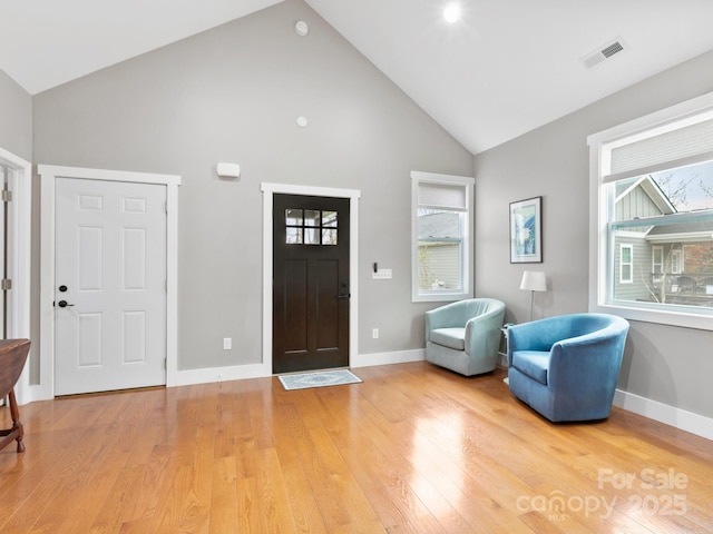 foyer entrance with high vaulted ceiling and light hardwood / wood-style flooring