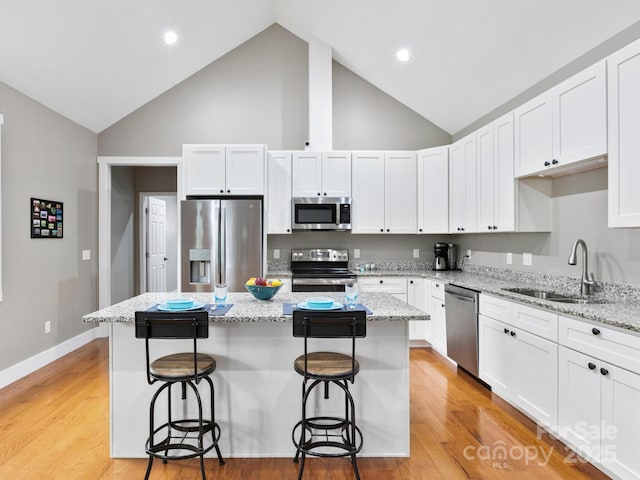 kitchen with stainless steel appliances, sink, a kitchen island, and white cabinets