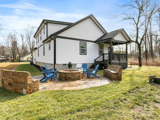 rear view of property featuring a patio, a fire pit, and a lawn