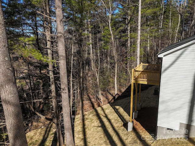 view of yard with a view of trees and a wooden deck