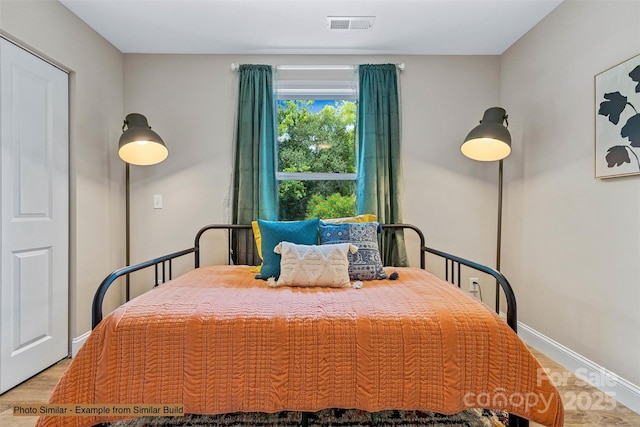 bedroom featuring visible vents, baseboards, and light wood finished floors