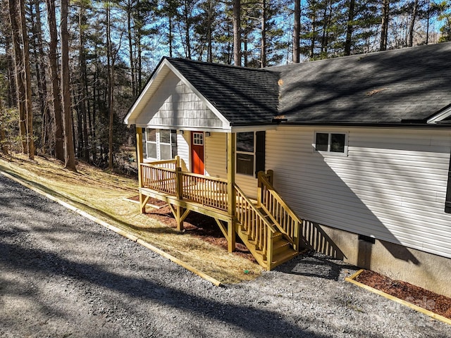 view of front facade with a shingled roof, crawl space, and a wooden deck