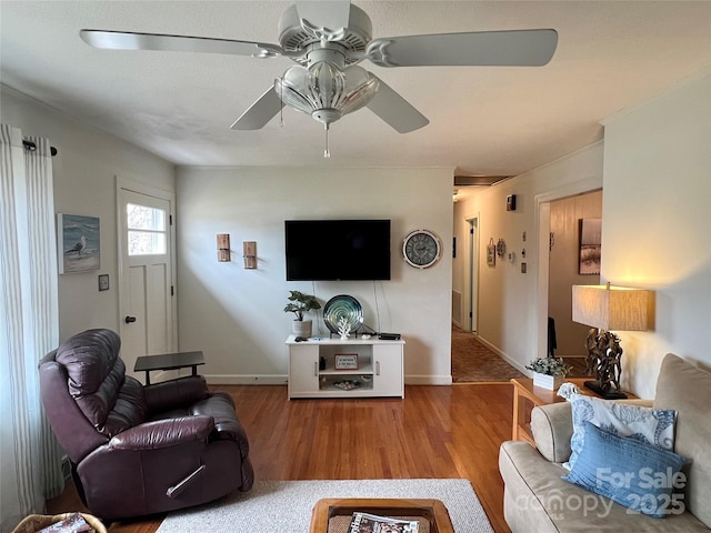 living room with a ceiling fan, baseboards, and wood finished floors