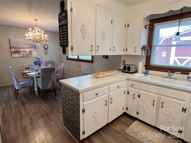 kitchen featuring a chandelier, dark wood-style flooring, a sink, white cabinetry, and light countertops