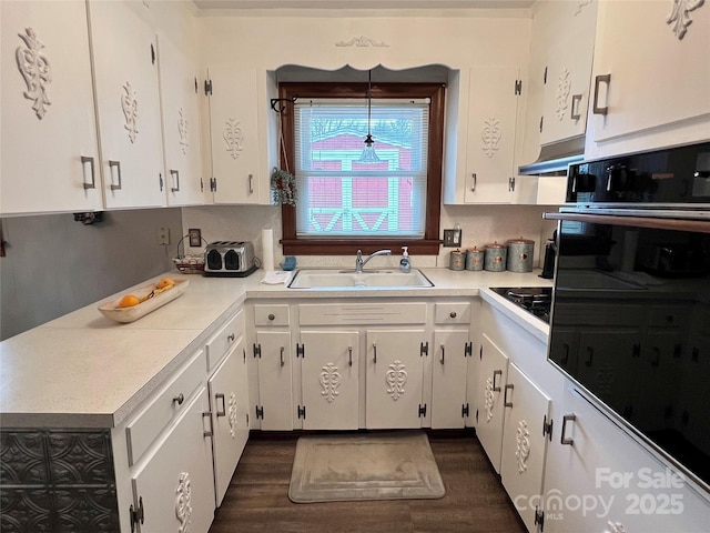 kitchen featuring black appliances, under cabinet range hood, light countertops, and a sink